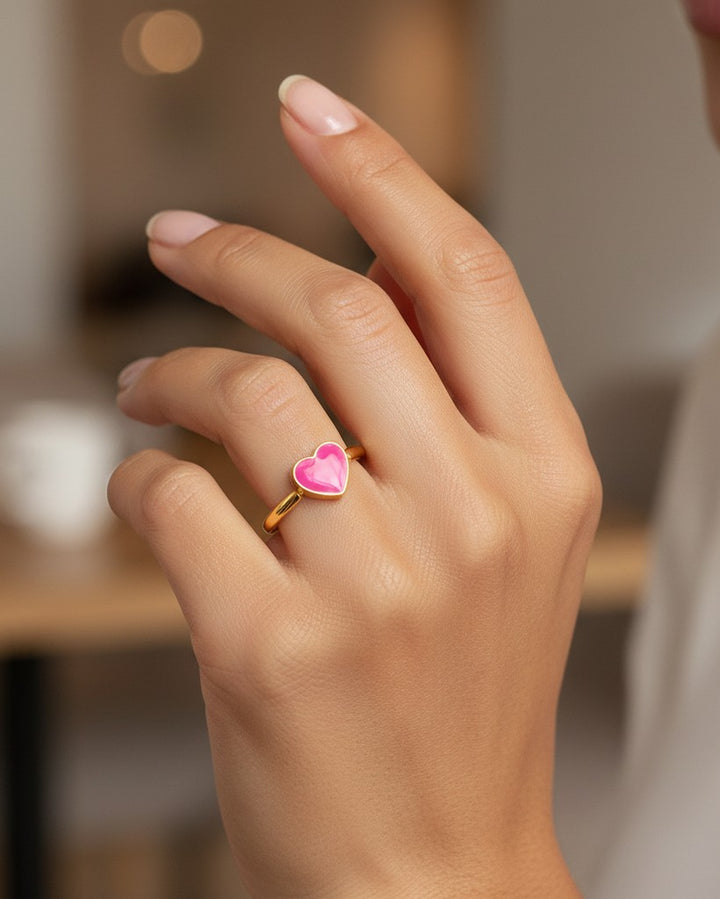 Elli Jewellery gold plated ring featuring a vibrant pink enamel heart on a woman's finger.