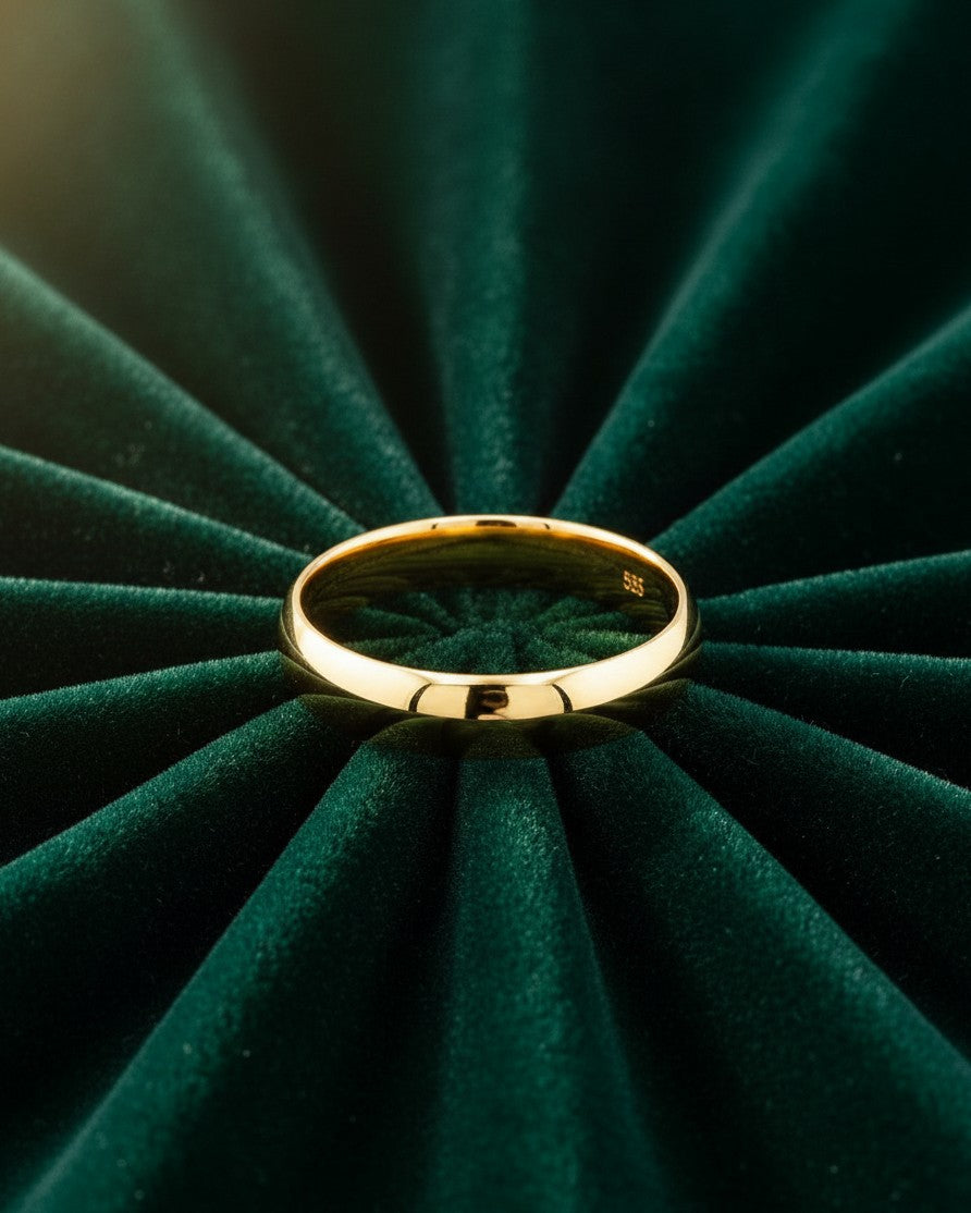 Elli Jewellery gold plated slim bangle bracelet resting on a dark green pleated velvet background