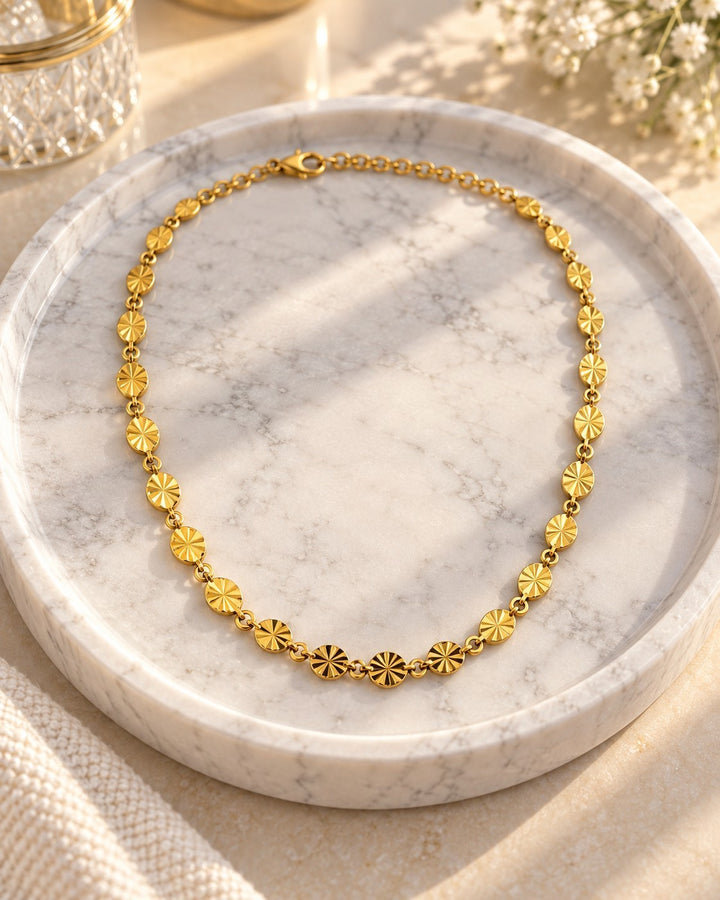 Elli Jewellery gold-plated dainty choker necklace with textured circular links on a marble tray.
