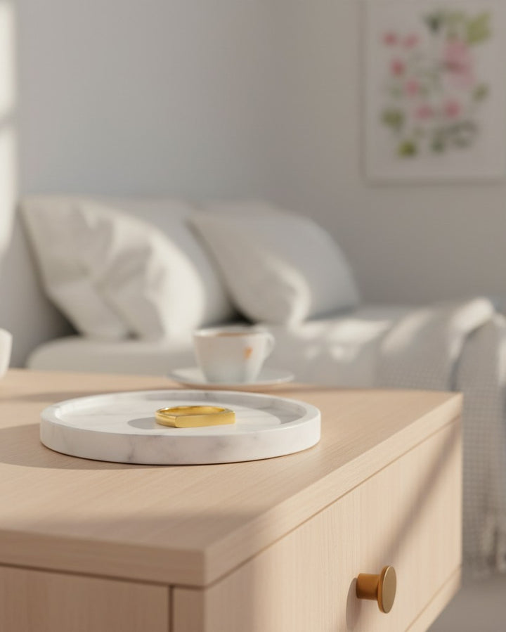 Elli Jewellery gold plated rectangular signet ring resting on a white marble tray in a bright, modern bedroom.