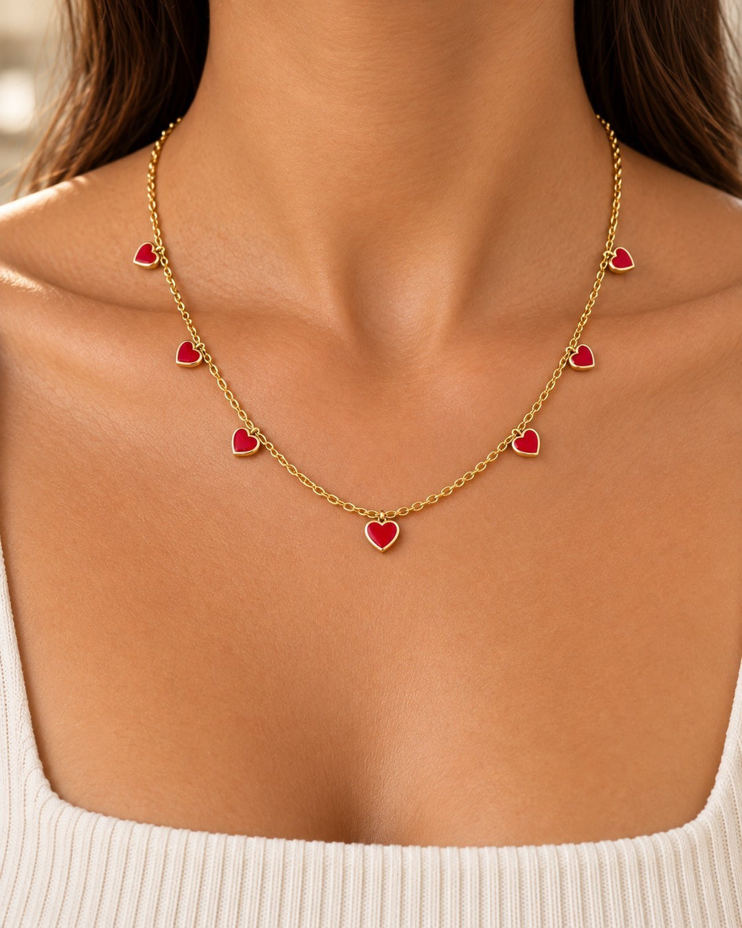 Elli Jewellery gold-plated chain necklace featuring multiple small ruby red crystal heart charms worn on a model