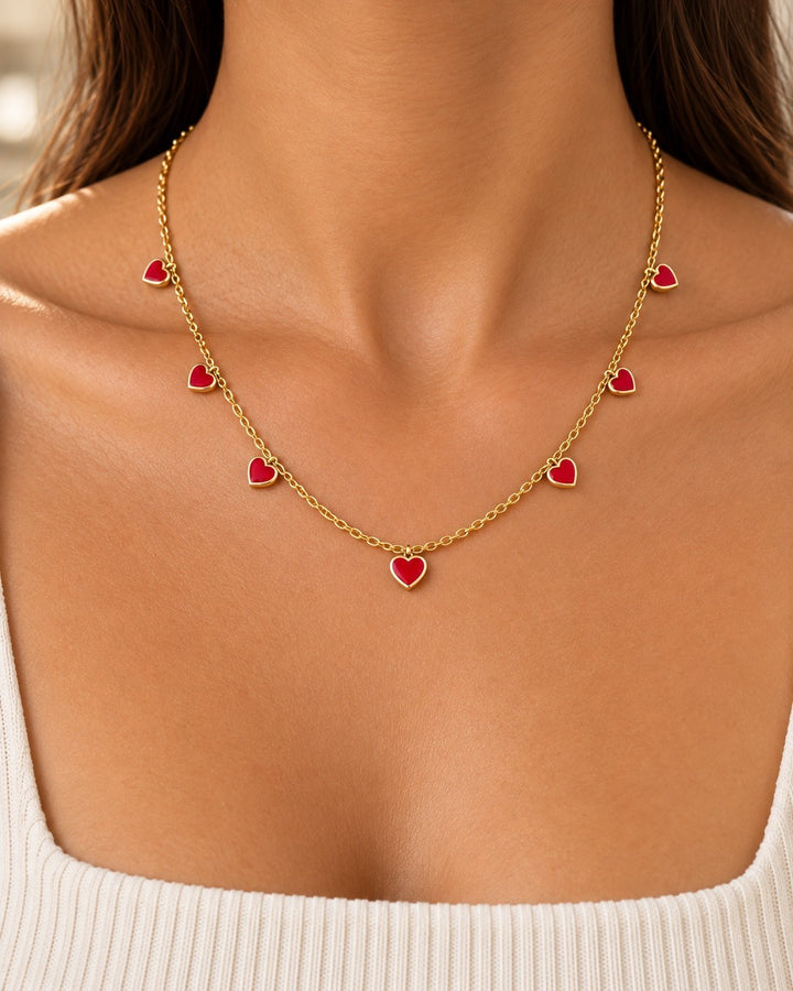 Elli Jewellery gold-plated chain necklace featuring multiple small ruby red crystal heart charms worn on a model
