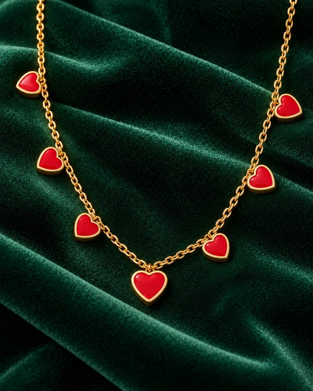 Elli Jewellery gold plated necklace featuring multiple vibrant ruby red crystal heart charms on a delicate chain.