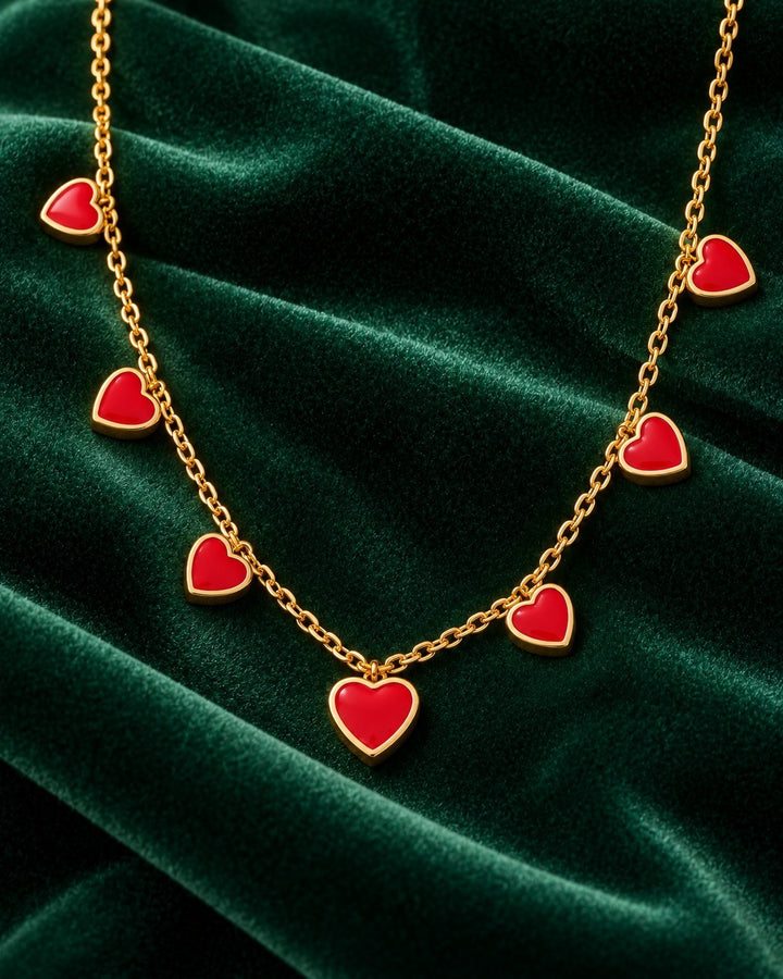 Elli Jewellery gold plated necklace featuring multiple vibrant ruby red crystal heart charms on a delicate chain.