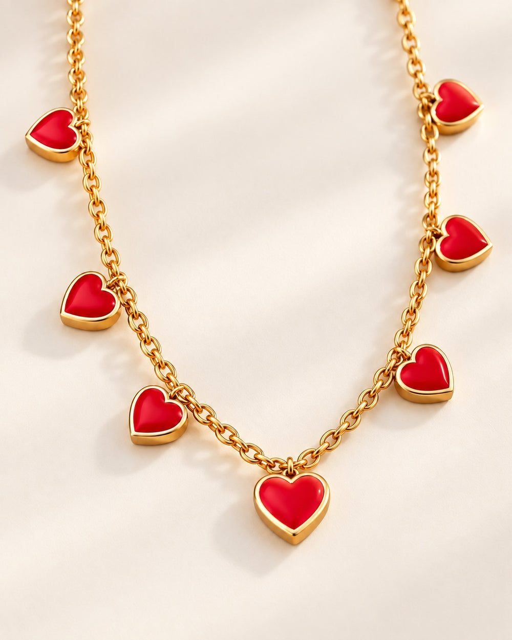 Elli Jewellery gold plated chain necklace featuring multiple ruby red crystal heart charms on a light background