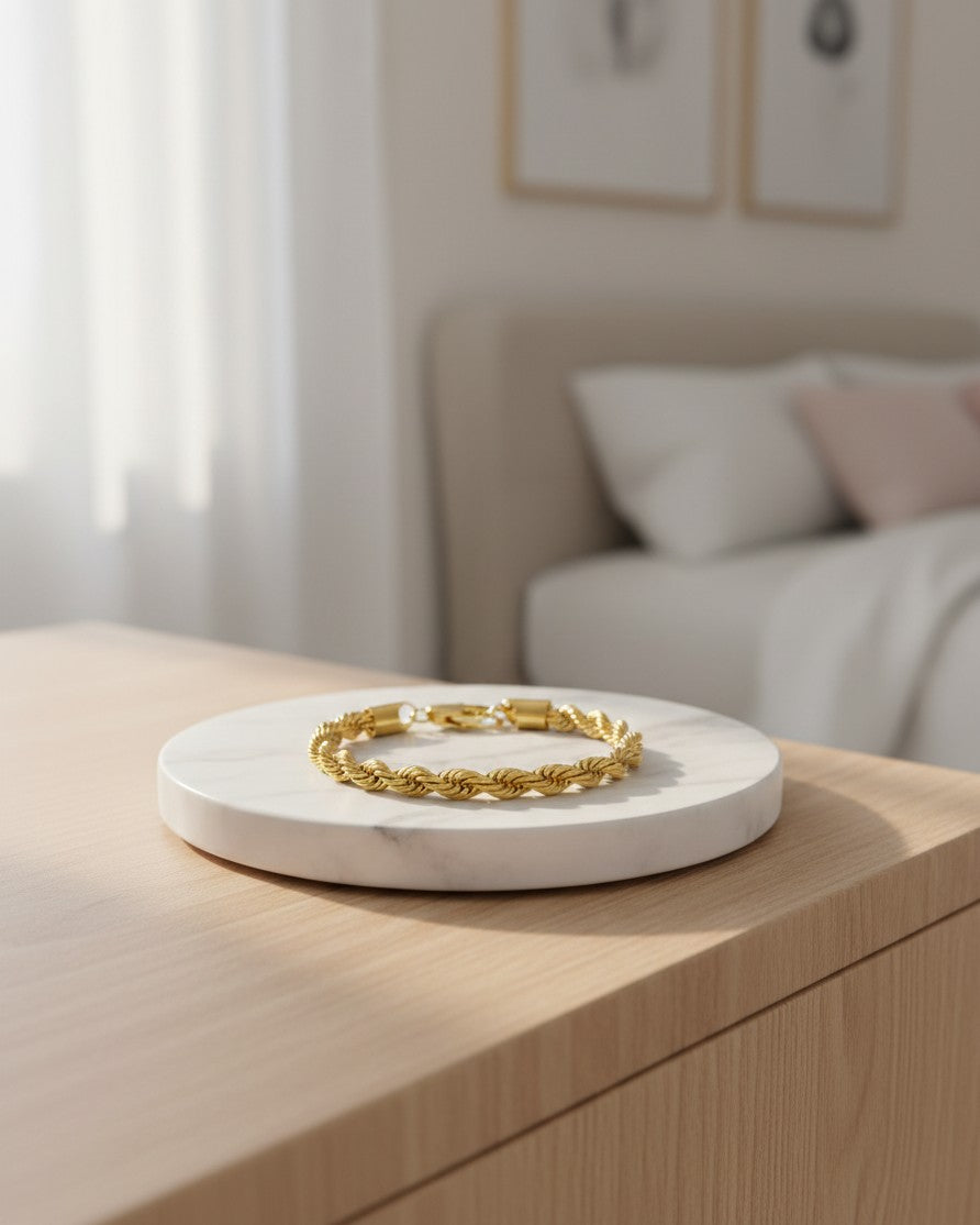 Elli Jewellery gold plated rope chain bracelet resting on a white marble display stand in a bright bedroom setting.