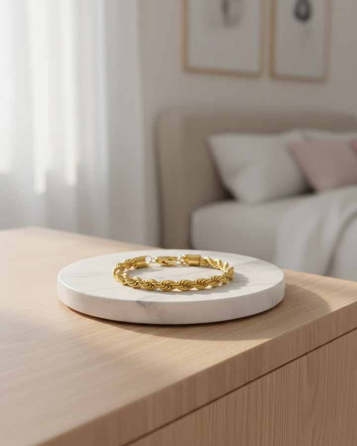 Elli Jewellery gold plated rope chain bracelet resting on a white marble display stand in a bright bedroom setting.