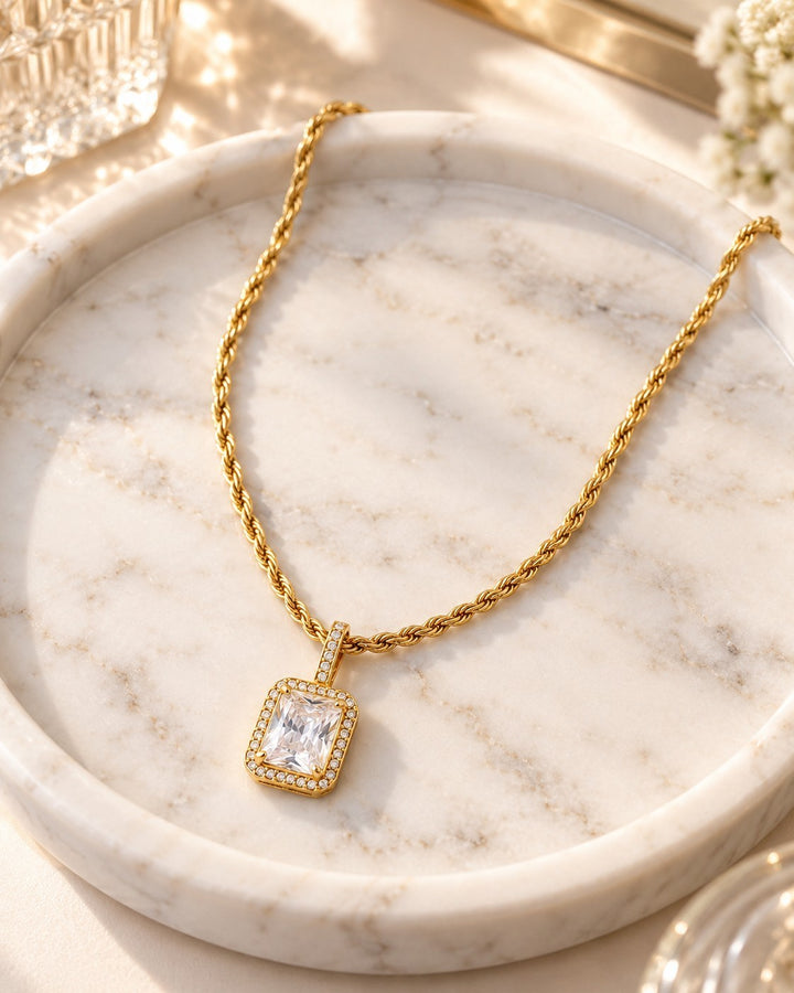 Elli Jewellery gold plated rope chain necklace with a rectangular cubic zirconia pendant on a marble tray.