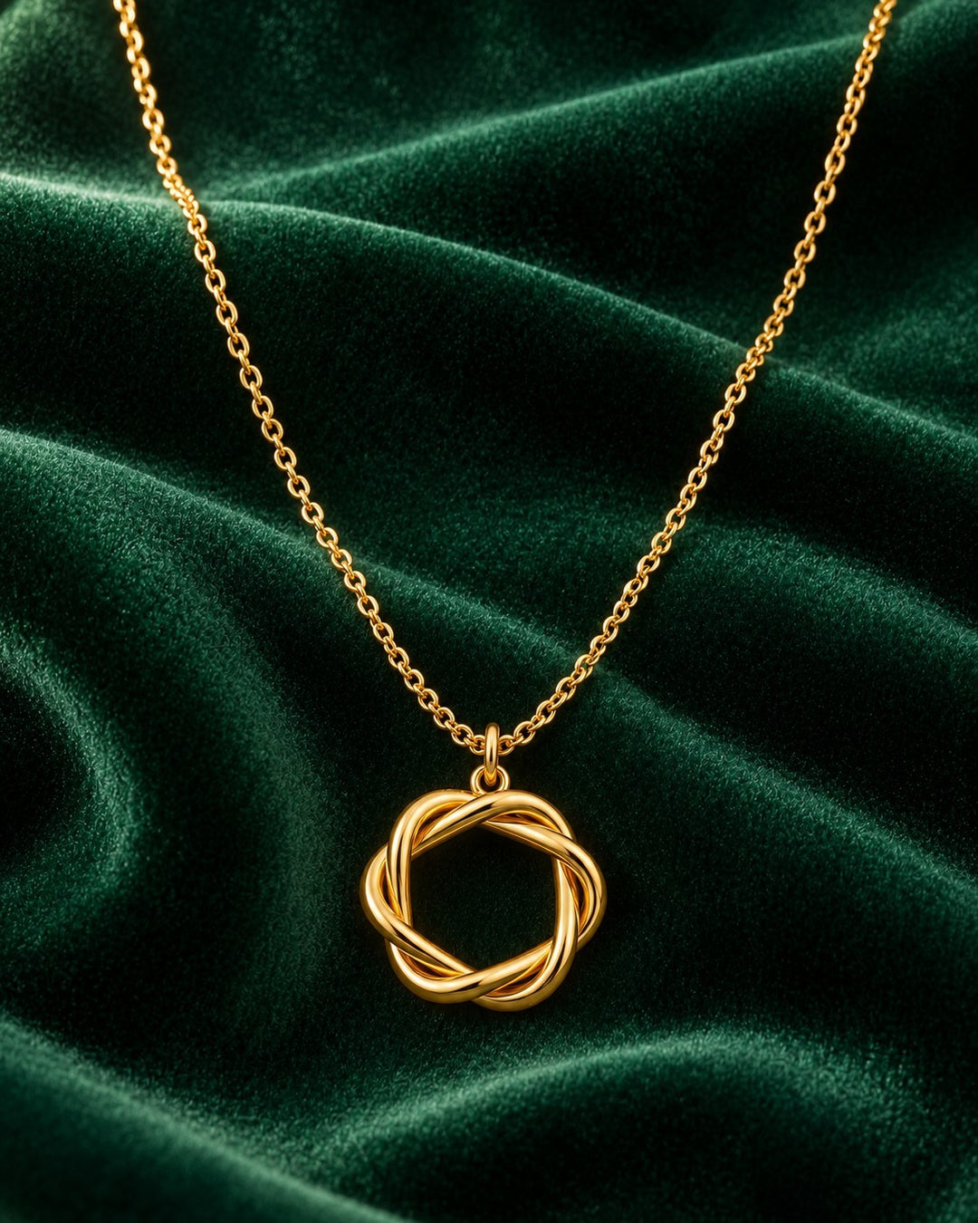 Elli Jewellery gold plated rope circle pendant necklace on a dark green velvet background