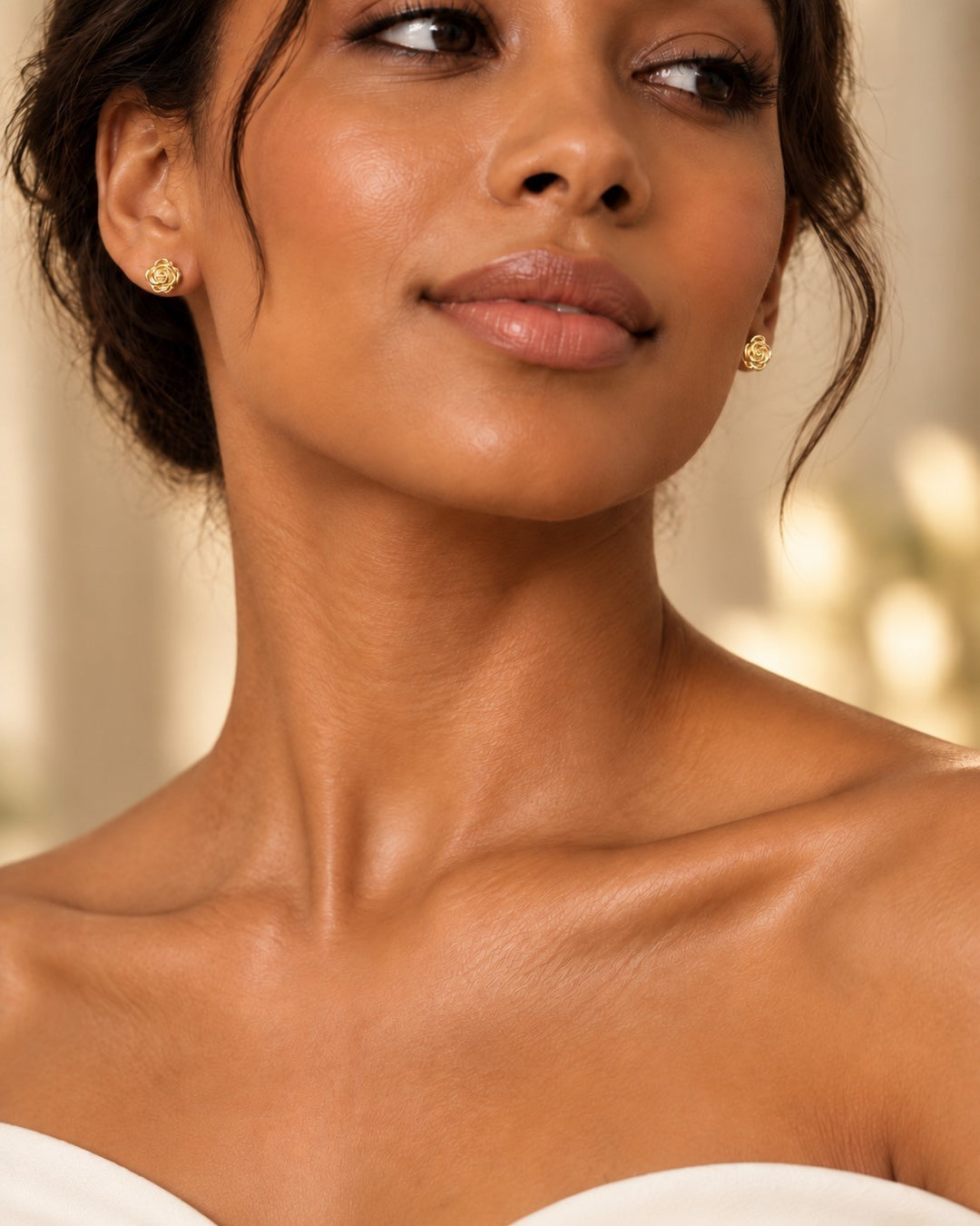 Model wearing Elli Jewellery gold plated rosette stud earrings with sculptural flower design on earlobes