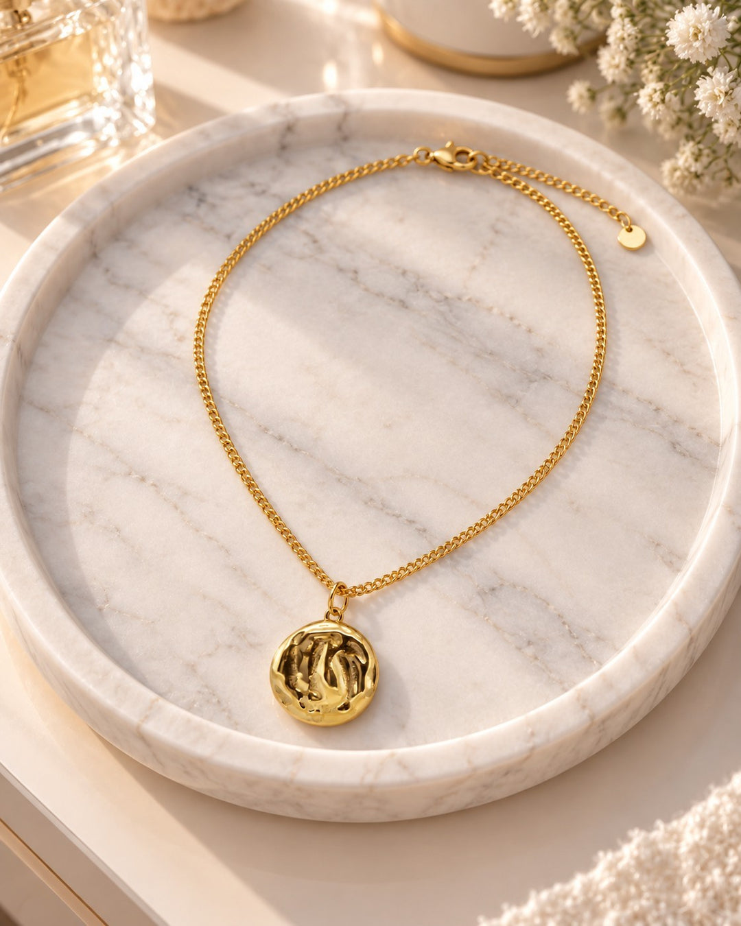 Elli Jewellery gold plated ocean shell pendant necklace with textured detail resting on a white marble tray.