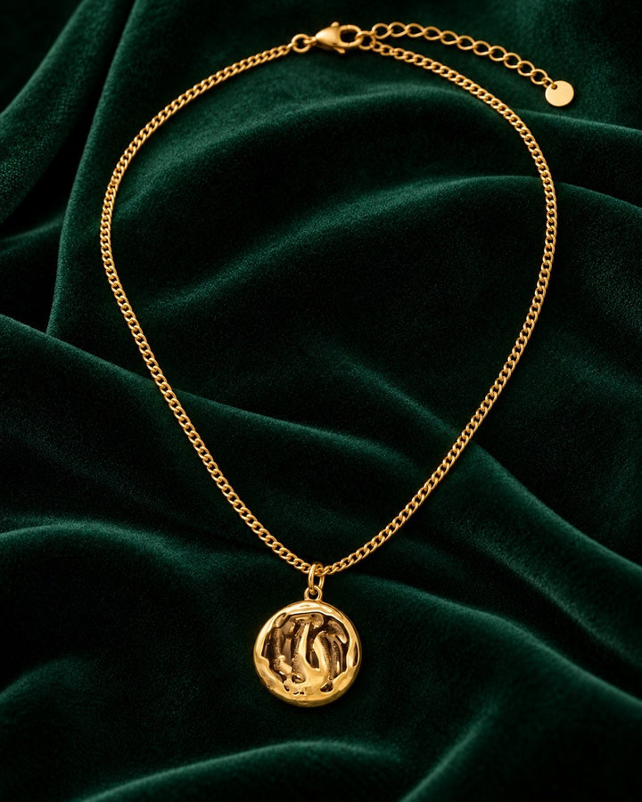 Elli Jewellery gold plated ocean shell pendant necklace with textured detail on a dark green velvet background