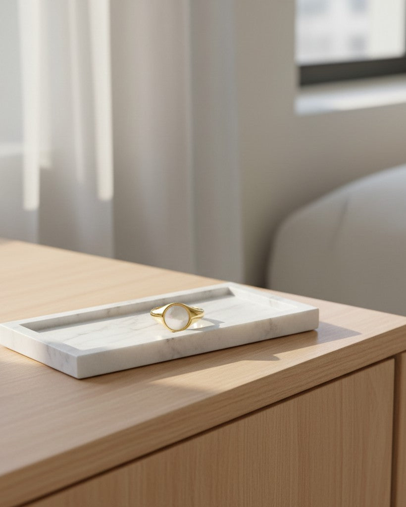 Elli Jewellery gold toned chunky ring with a white shell inlay resting on a white marble tray.