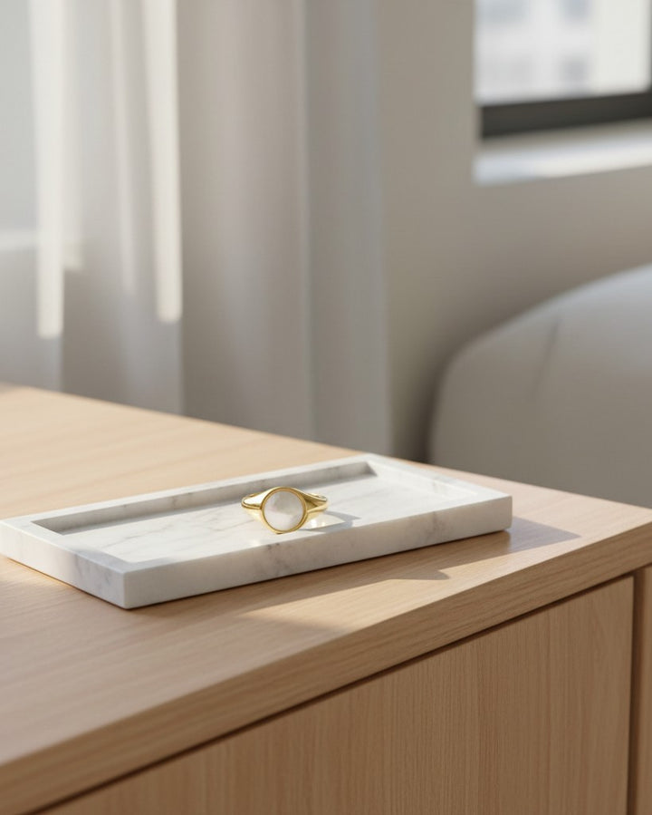 Elli Jewellery gold toned chunky ring with a white shell inlay resting on a white marble tray.