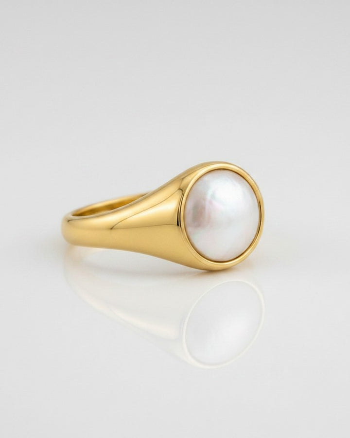 Elli Jewellery gold-toned chunky signet ring featuring a smooth, iridescent white shell inlay on a reflective surface.