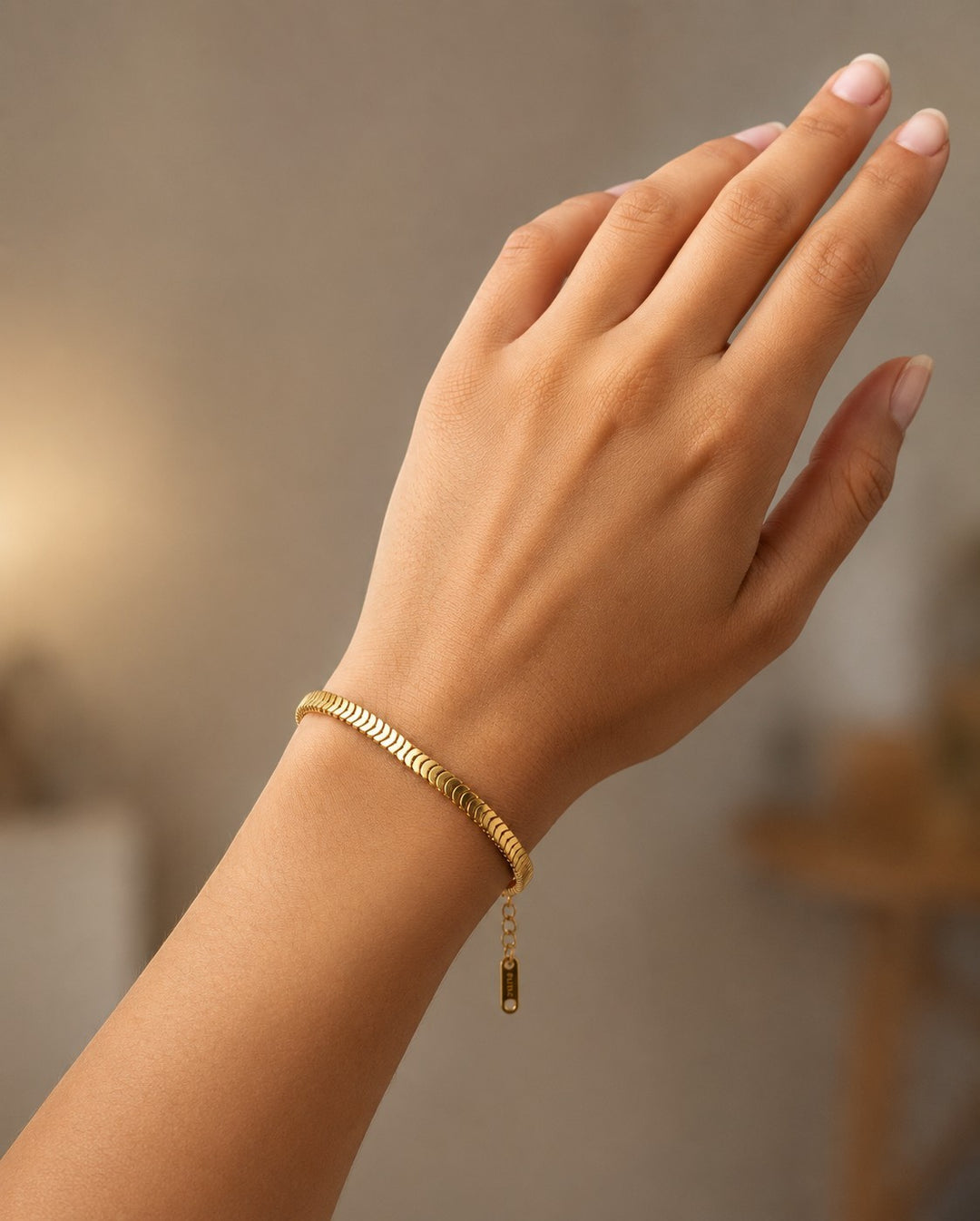Elli Jewellery gold plated snake disc chain bracelet worn on a woman's wrist, featuring a sleek fluid design.