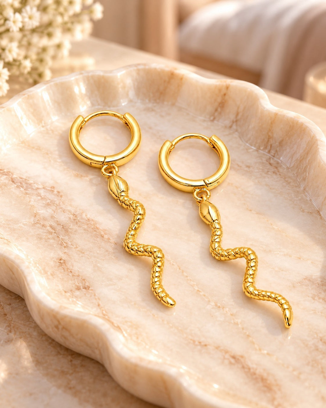 Elli Jewellery gold plated huggie hoop earrings featuring a dangling snake charm with a textured reptilian finish.