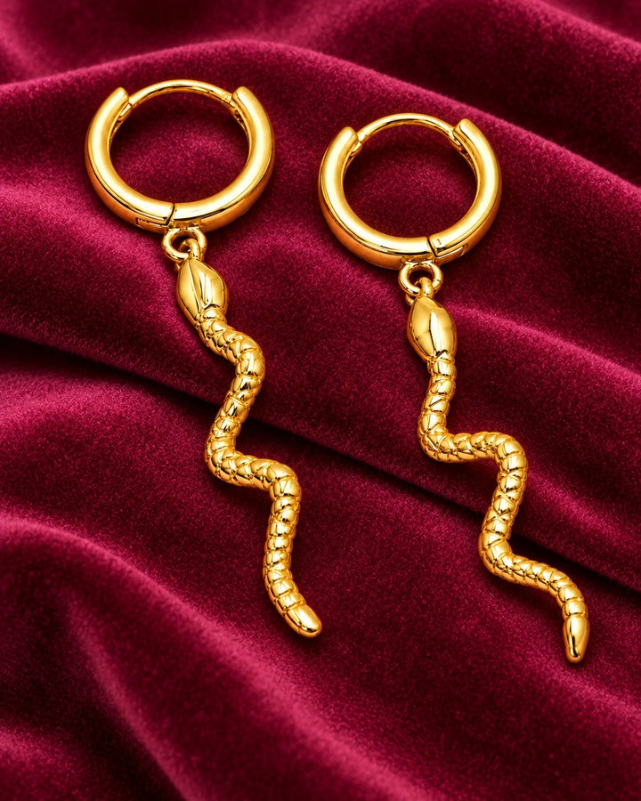 Elli Jewellery gold plated huggie hoop earrings featuring a dangling snake charm with detailed reptilian texture.