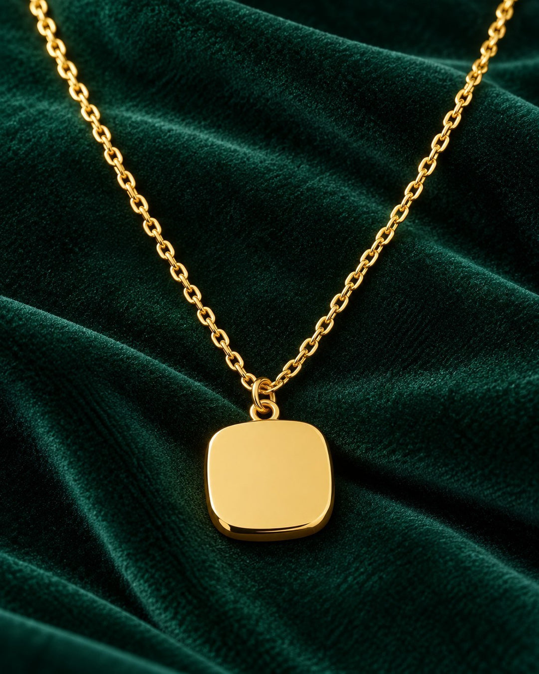 Elli Jewellery gold plated geometric square pendant necklace on a dark green velvet background