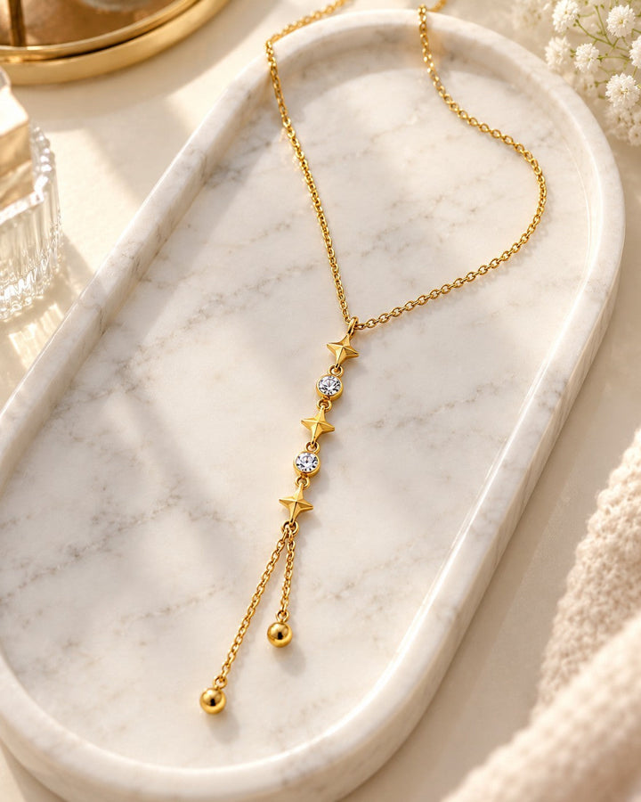Elli Jewellery gold plated drop necklace featuring star charms and crystals on a marble tray