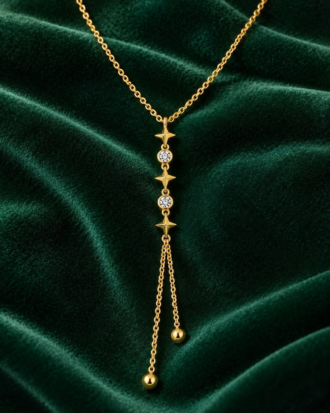 Elli Jewellery gold plated necklace featuring star motifs and sparkling crystals on a dark green velvet background