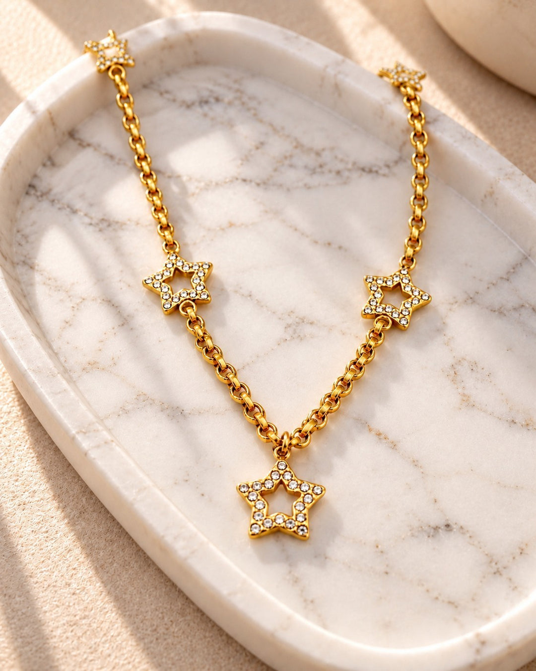 Elli Jewellery gold plated celestial star necklace with crystal accents on a marble tray