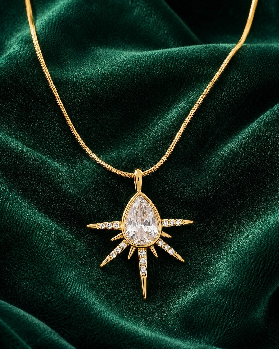 Elli Jewellery gold plated starburst pendant necklace featuring a pear-shaped crystal and pavé stones on a snake chain.