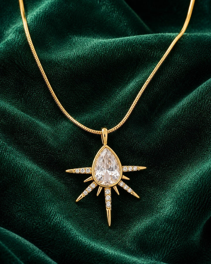 Elli Jewellery gold plated starburst pendant necklace featuring a pear-shaped crystal and pavé stones on a snake chain.