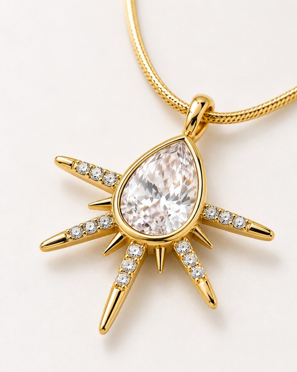 Elli Jewellery gold plated starburst pendant necklace featuring a central pear-shaped crystal and pavé stone accents.