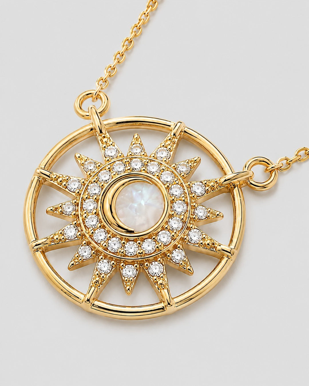 Elli Jewellery gold plated starburst medallion pendant with a cream cabochon center and sparkling crystal rays.