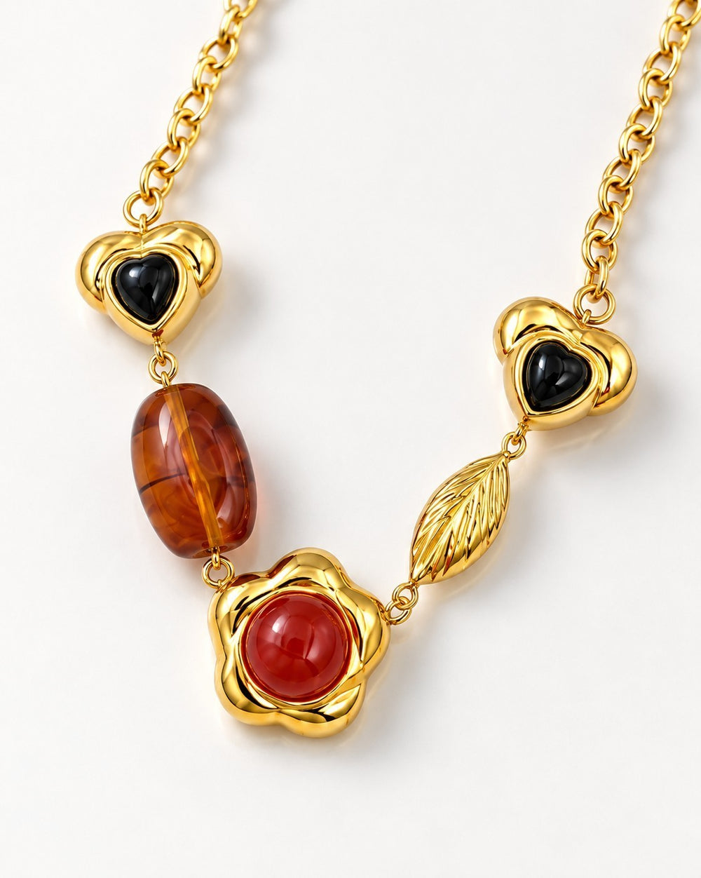 Elli Jewellery gold plated statement necklace featuring heart charms, amber beads, and a red floral pendant.