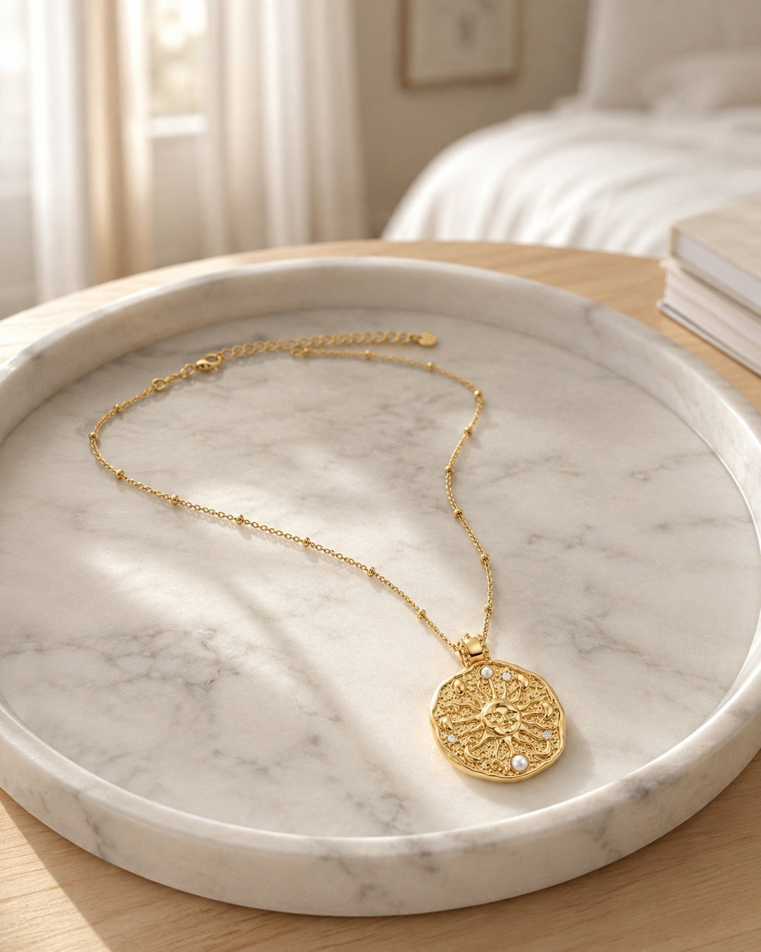 Elli Jewellery gold plated celestial sun medallion necklace with pearl accents on a marble tray