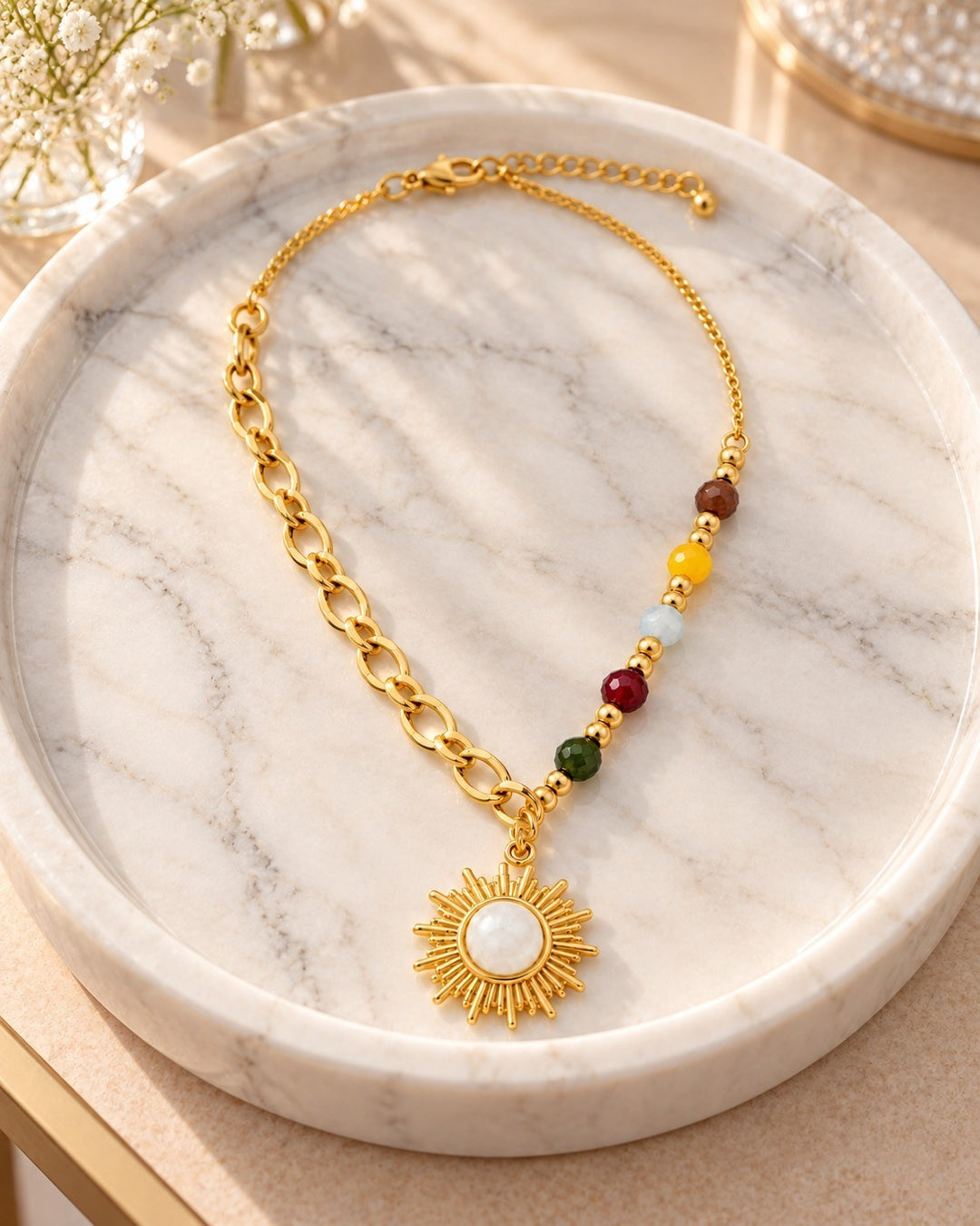 Elli Jewellery gold plated sunbeam pendant necklace with multicolour enamel beads on a marble tray