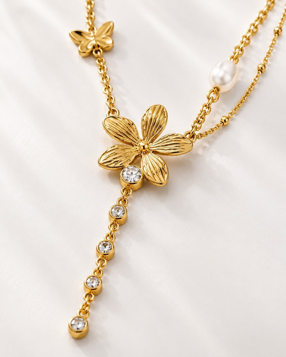 Elli Jewellery gold plated sunflower charm necklace with crystal accents, a butterfly charm, and a small pearl.