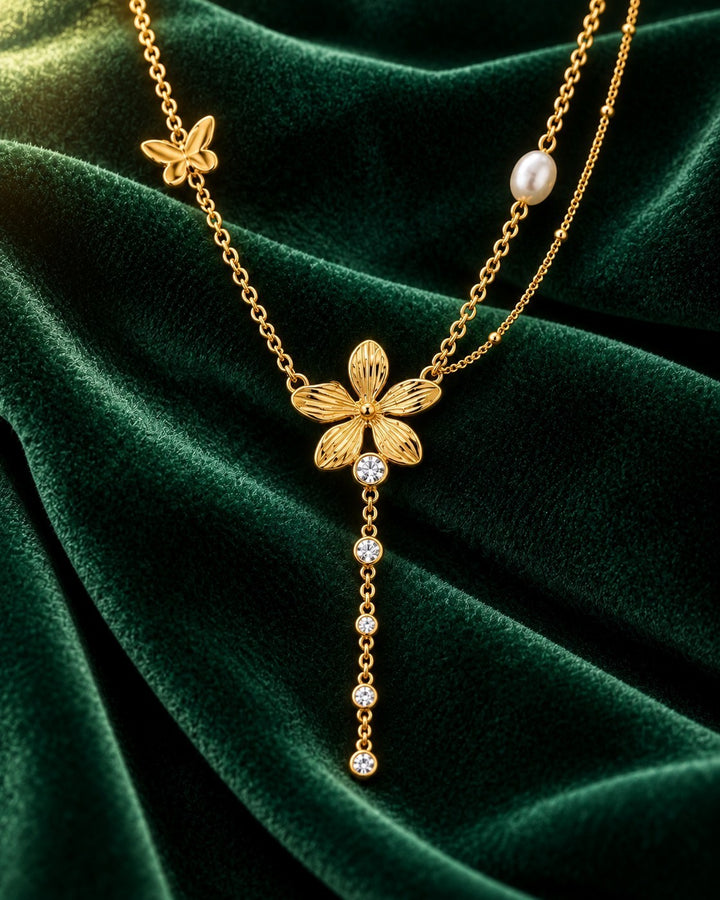 Elli Jewellery gold plated sunflower charm necklace with a butterfly, pearl, and crystal drop on green velvet.