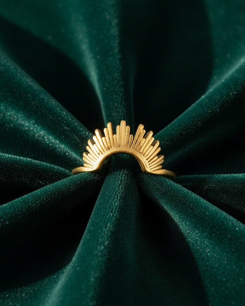 Elli Jewellery gold plated sunflower stacking ring with sunburst petal design on a dark green velvet background.