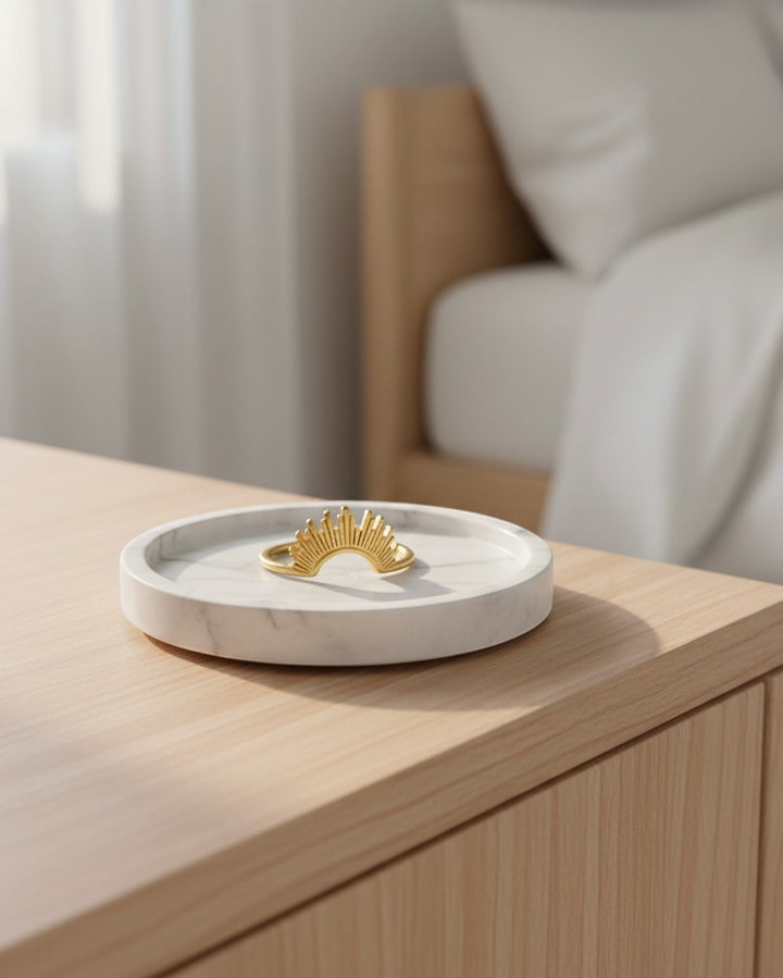 Elli Jewellery gold plated sunflower stacking ring resting on a white marble tray on a wooden surface.