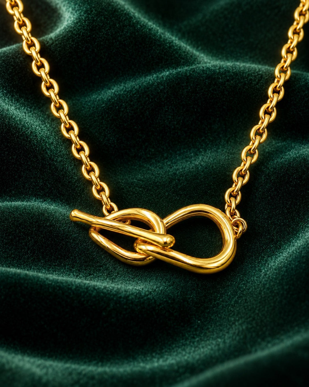 Elli Jewellery gold plated minimalist T-bar pendant necklace on a dark green velvet background