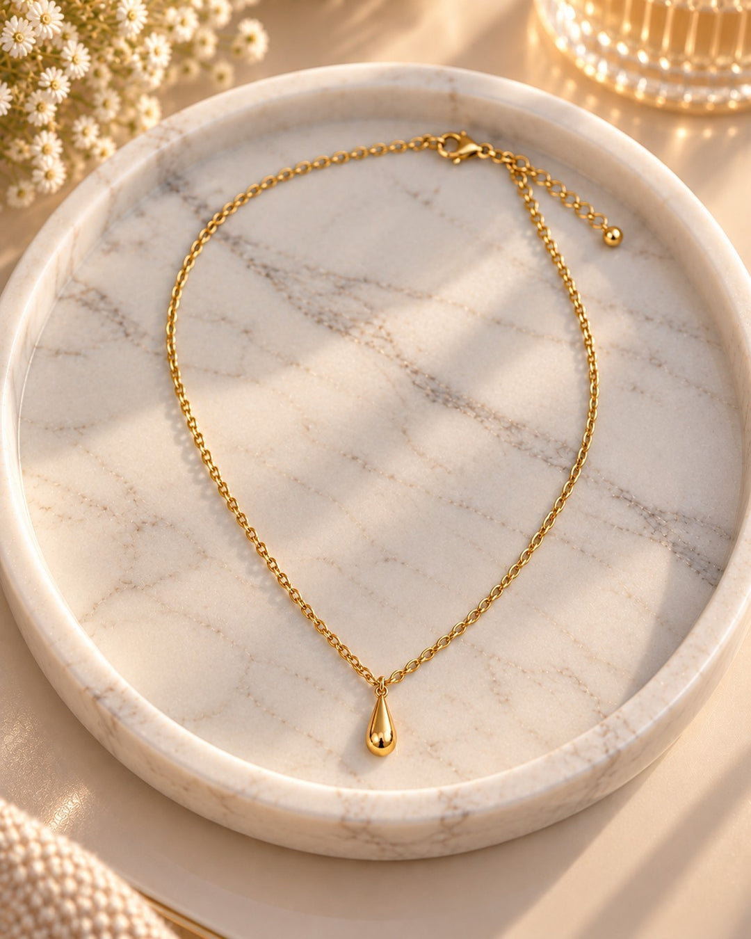 Elli Jewellery gold plated waterproof chain necklace with a delicate teardrop pendant resting on a marble tray.