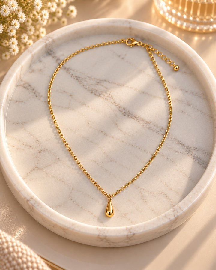 Elli Jewellery gold plated waterproof chain necklace with a delicate teardrop pendant resting on a marble tray.