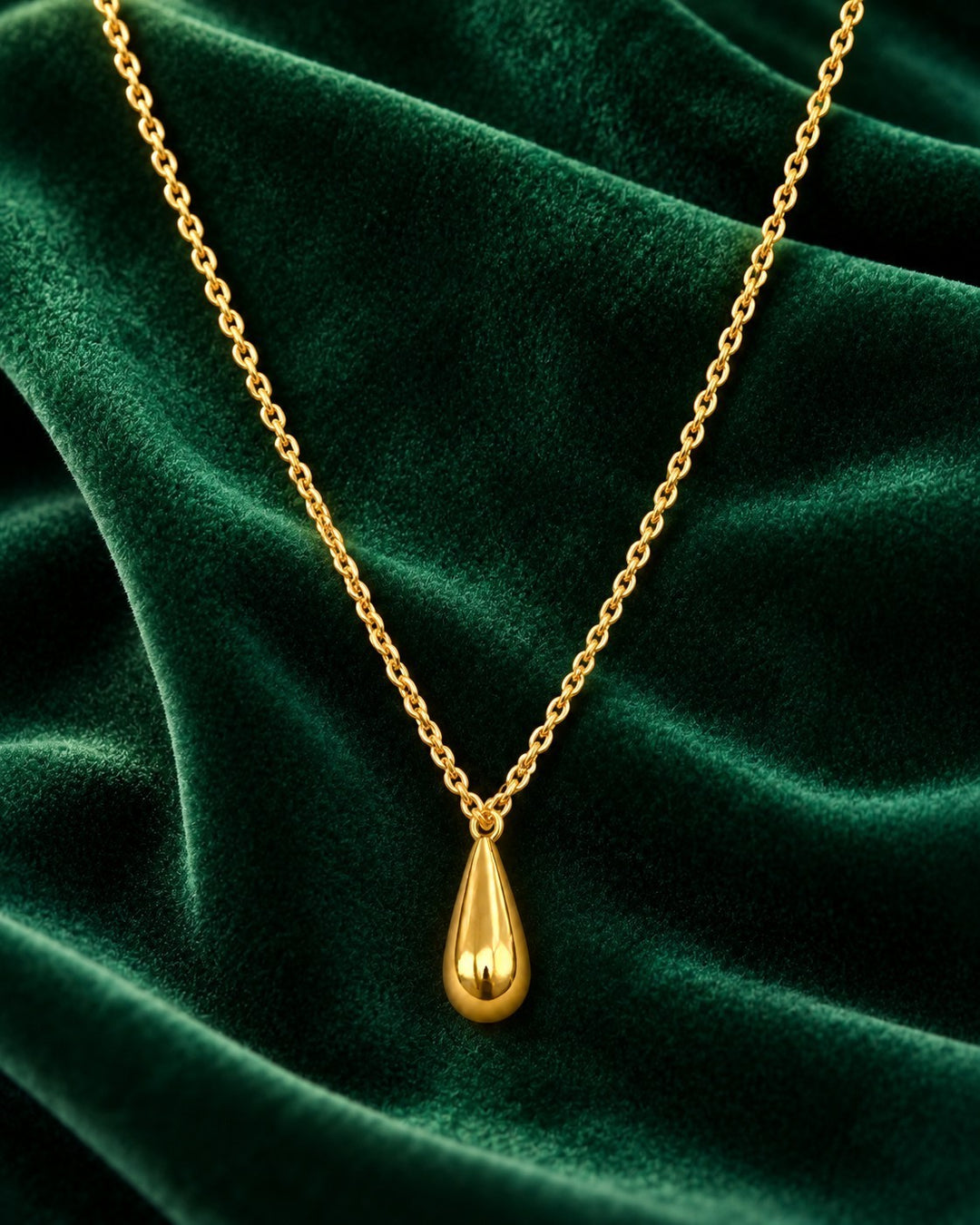Elli Jewellery gold plated waterproof teardrop pendant necklace on a rich green velvet background