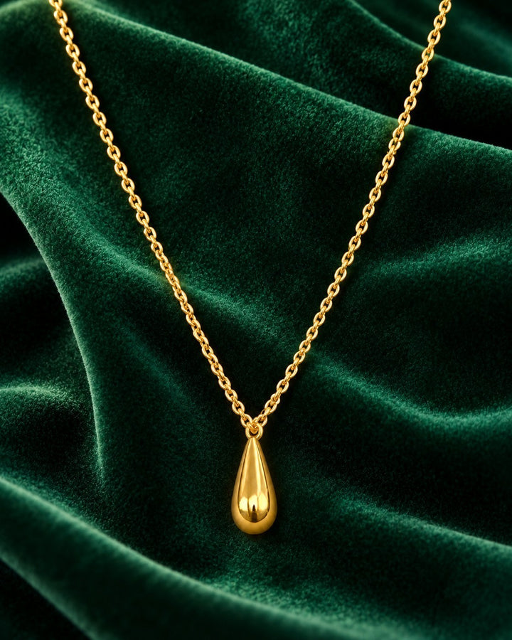 Elli Jewellery gold plated waterproof teardrop pendant necklace on a rich green velvet background