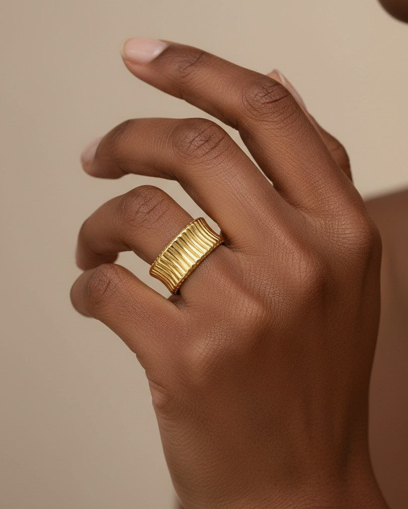 Elli Jewellery gold plated waterproof inverse band ring with a textured, ribbed finish worn on a finger.