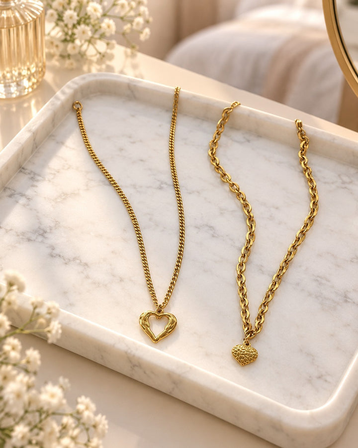Elli Jewellery gold plated waterproof necklaces featuring textured heart pendants on a marble tray.