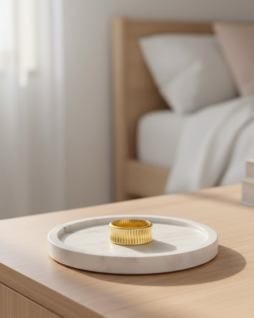 Elli Jewellery gold plated waterproof inverse band ring with a textured finish resting on a white marble tray.