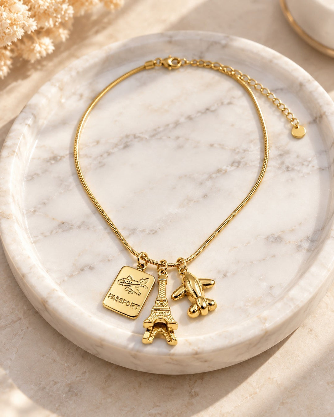 Elli Jewellery gold plated necklace featuring Eiffel Tower, passport, and airplane charms on a delicate chain