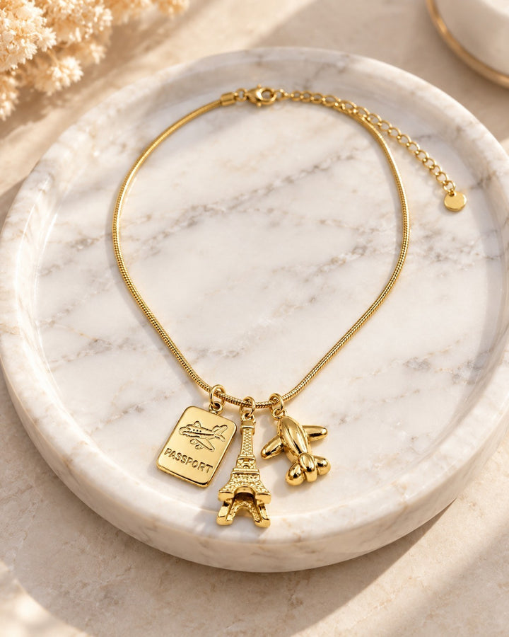 Elli Jewellery gold plated necklace featuring Eiffel Tower, passport, and airplane charms on a delicate chain