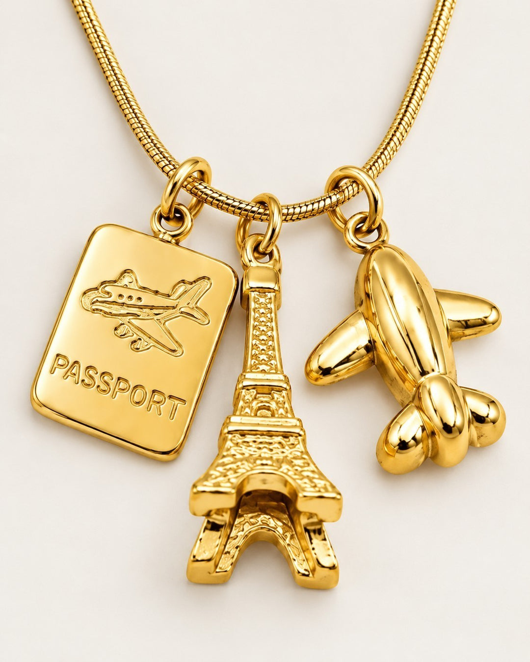Elli Jewellery gold plated necklace featuring Eiffel Tower, passport, and airplane charms on a delicate chain