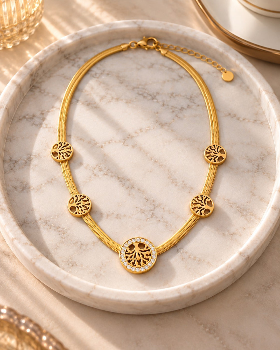 Elli Jewellery gold plated Tree of Life necklace with crystal accents on a marble tray