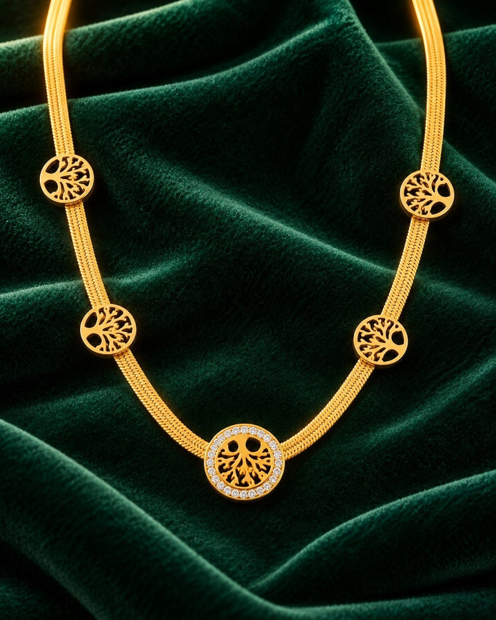 Elli Jewellery gold plated Tree of Life necklace with crystal accents on a dark green velvet background.